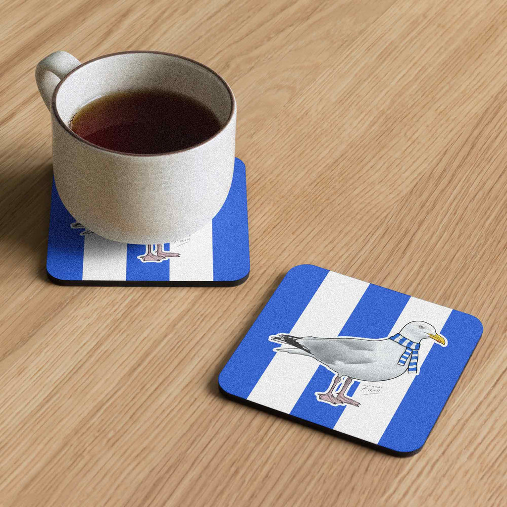 Cup of tea on a coaster with a seagull design on a wooden surface